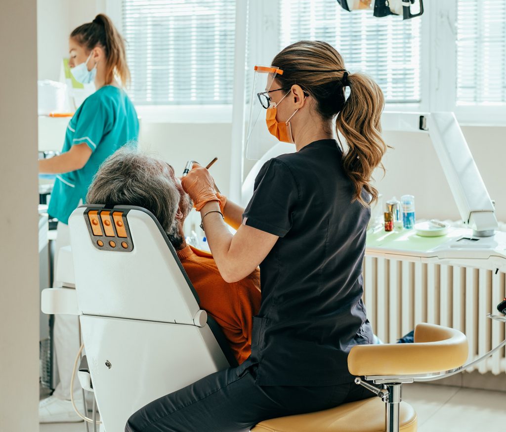 About Us 1 Dentist in Fairfield, CA treating an older patient while an assistant works nearby in the family dental office