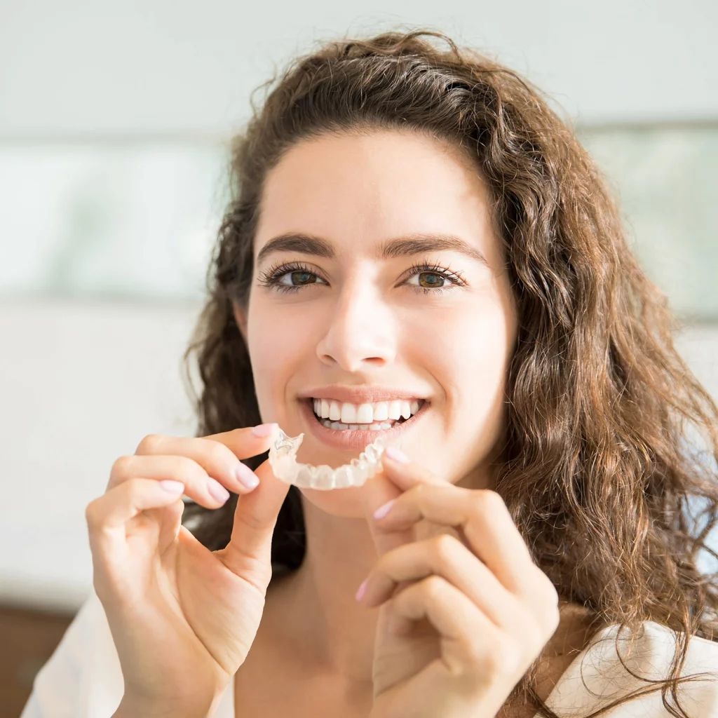 Clearcorrect 1 Smiling woman holding a clear Invisalign aligner at Po Dental Group in Fairfield