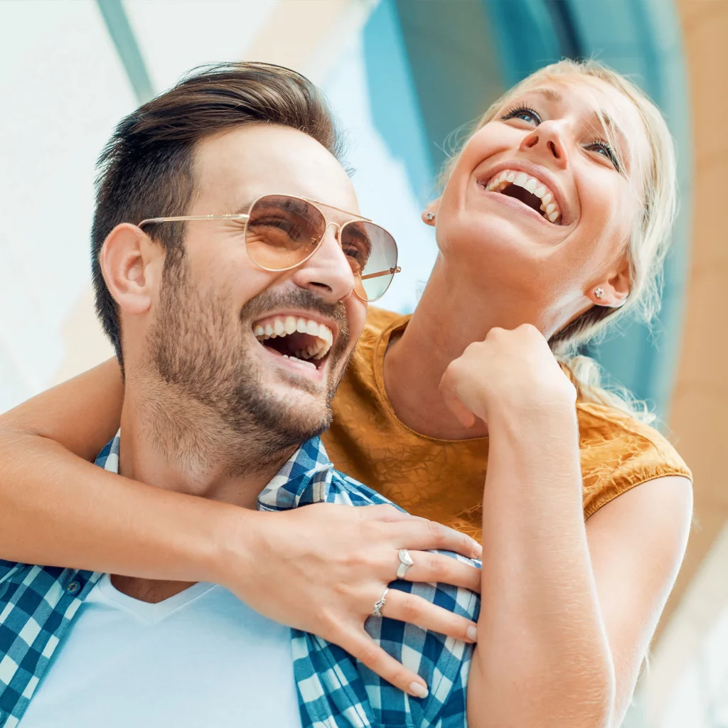 Cosmetic & Restorative Dentistry 1 Couple laughing outdoors with bright healthy smiles at Po Dental Group in Fairfield